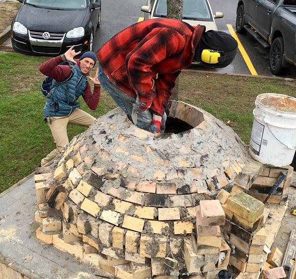 Construction of the Wolfville Community Oven, with Travis working inside the oven structure.